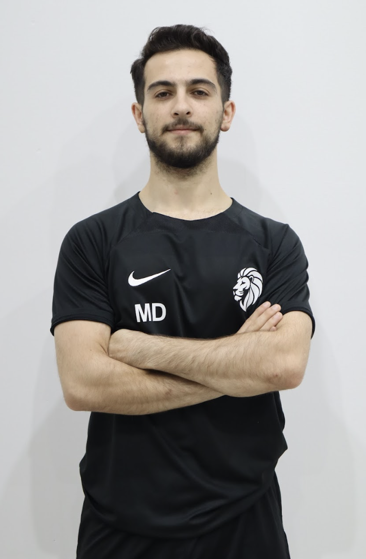 Muhammet Demiroz — Coach at Alp Academy, arms crossed in black Nike kit